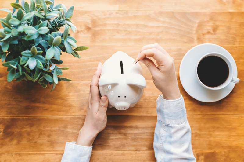 Woman holding a white piggy bank on a wooden desk